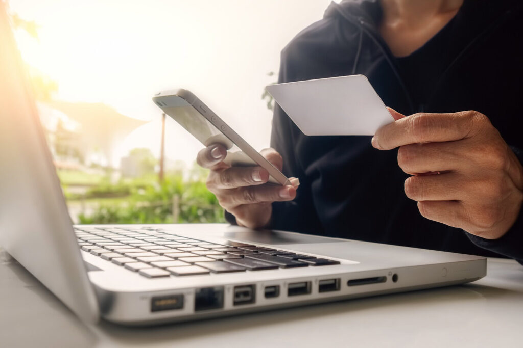 A man making secure online payments with a phone and a card on his laptop
