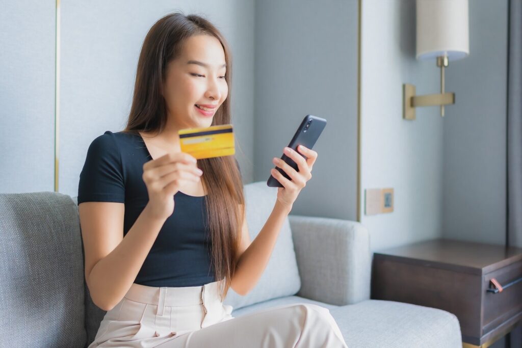 A young woman holds a phone and a credit card, settling an online payment via BNPL for business.