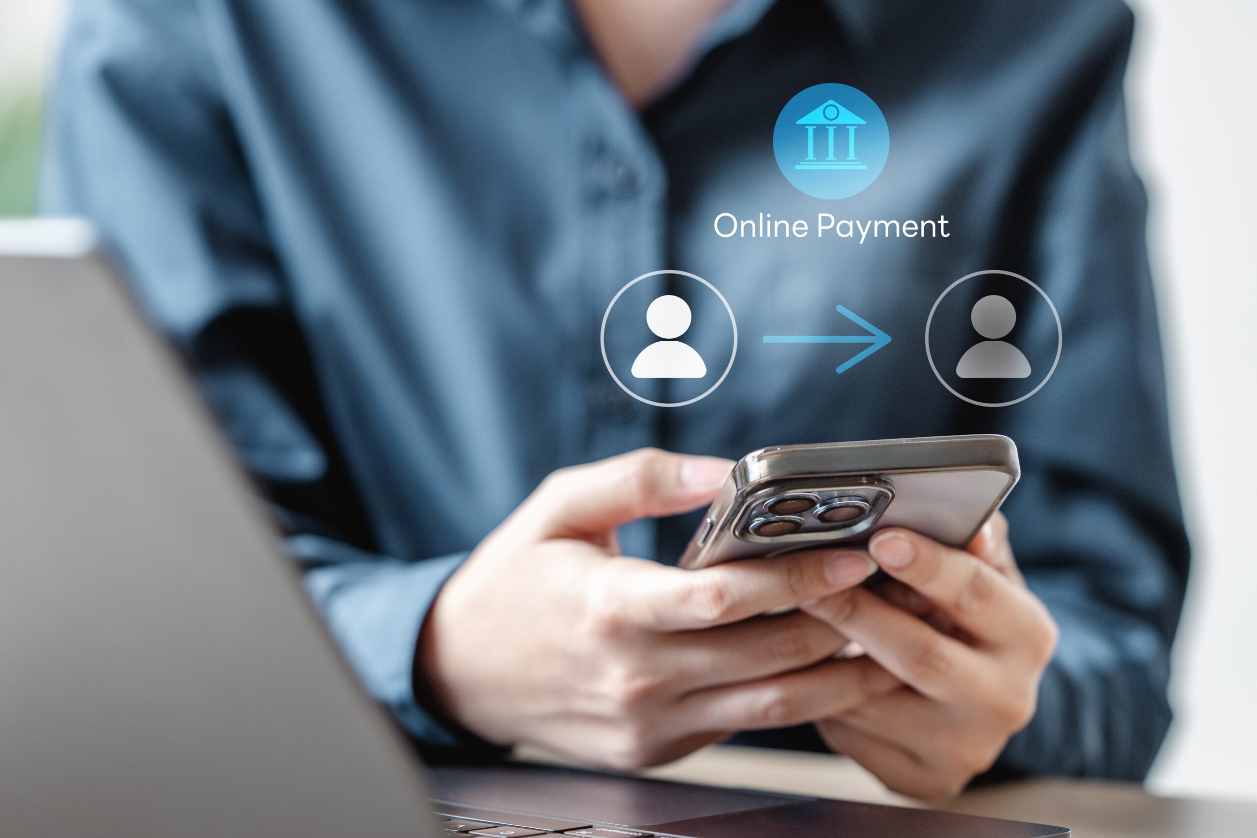Person holding smartphone with online payment icons showing a digital bank transfer in progress