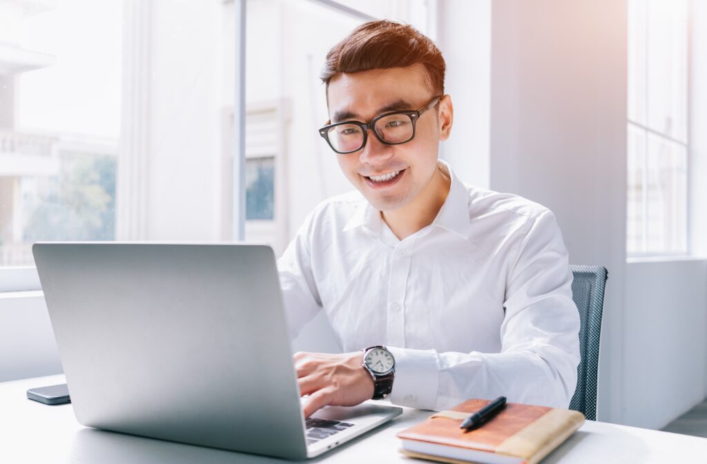 A young businessman works on his laptop, setting up e-invoicing for his Malaysian SME.