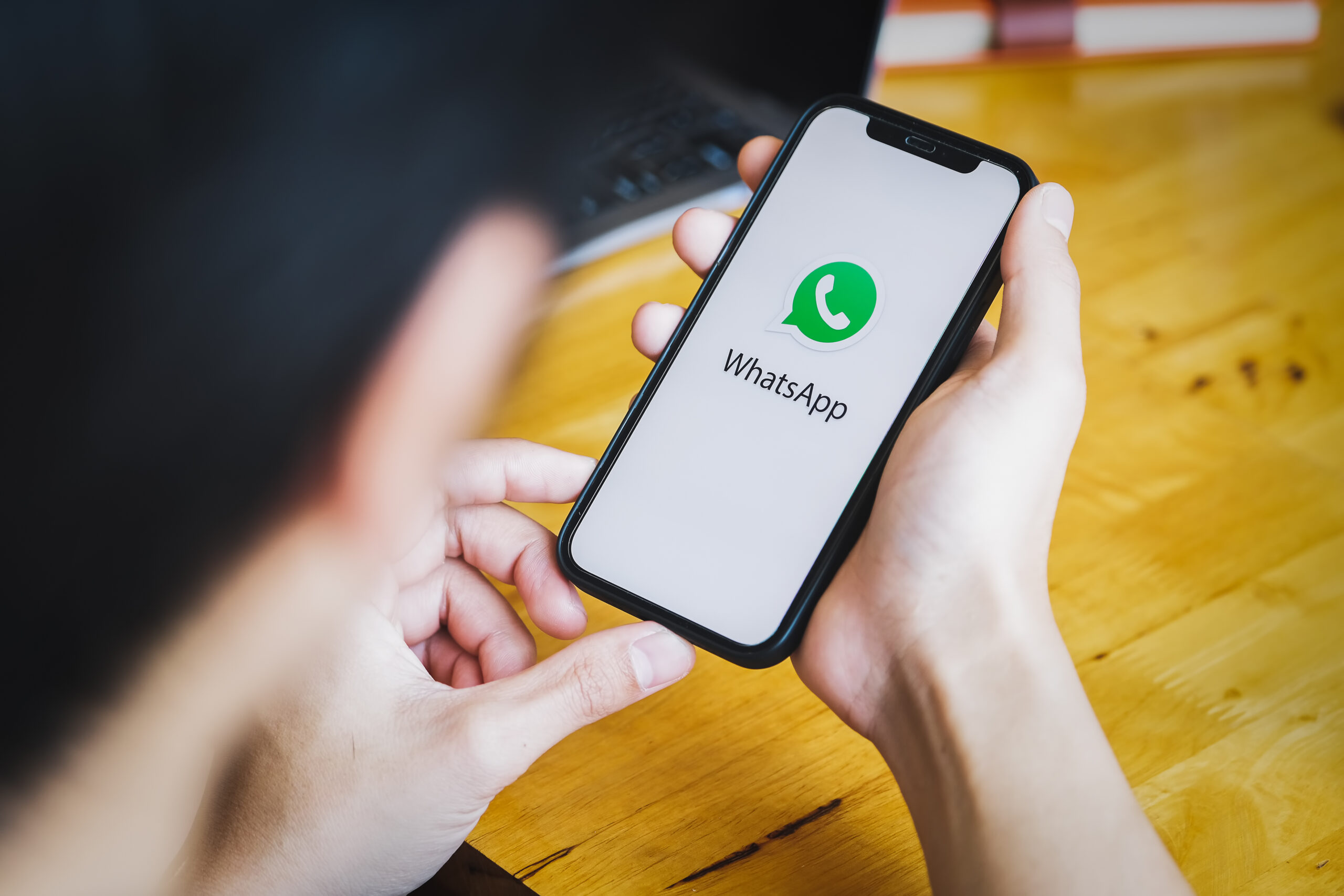 Close up of hands holding smartphone with WhatsApp open on screen