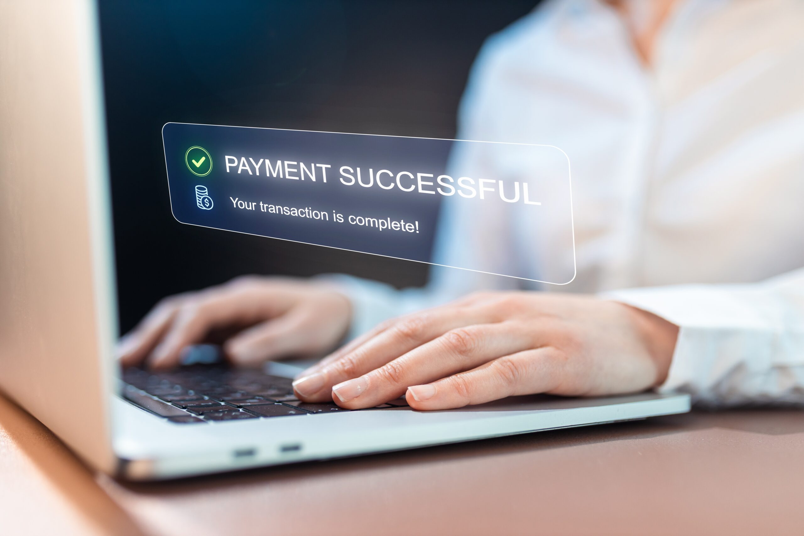 Person typing on laptop with a payment successful notification floating on screen
