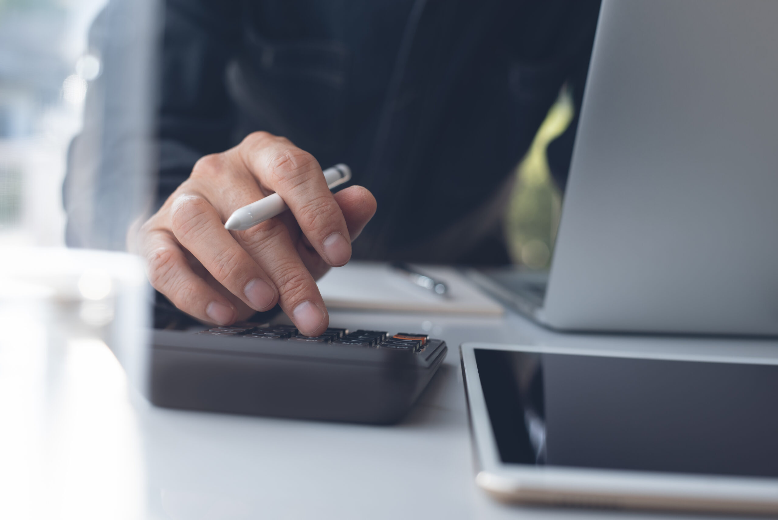 Finance team member reconciling transactions using a calculator manually
